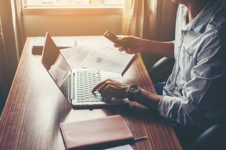 businessman hands using cell phone with laptop at office desk 1024x683